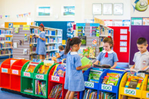 Students looking through books while others read in a bright, colourful library