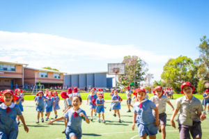 Dozens of students smiling and running in an open green field