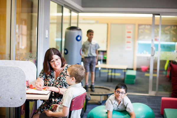 A student learning with a teacher while two students are active in a specialised learning space