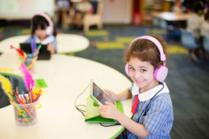 Young student using tablet and wearing headphones smiling