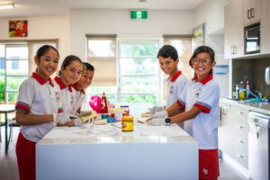 Five students smiling and preparing sandwiches for community charity