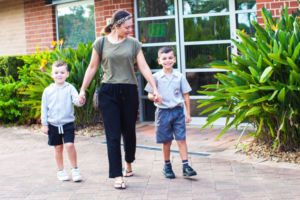 Mother and two sons walking by front office of John the Baptist Catholic Primary School Bonnyrigg Heights