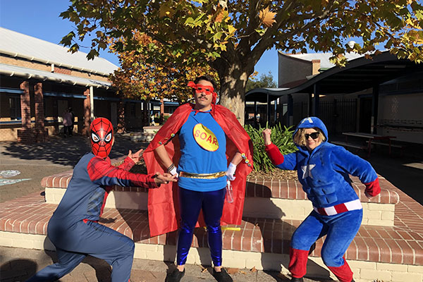 Three staff dressed in costume as superheros