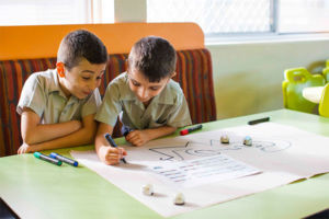 Two students working on a drawing together and smiling